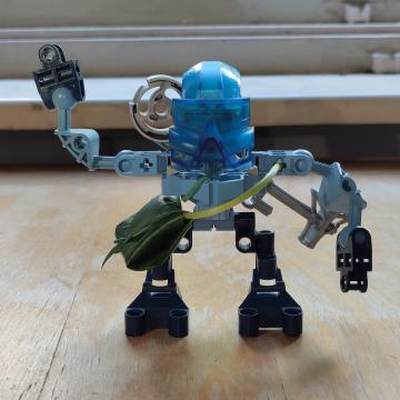 Hahli Lego figure, wearing a messenger bag crafted from a leaf, waving goodbye.