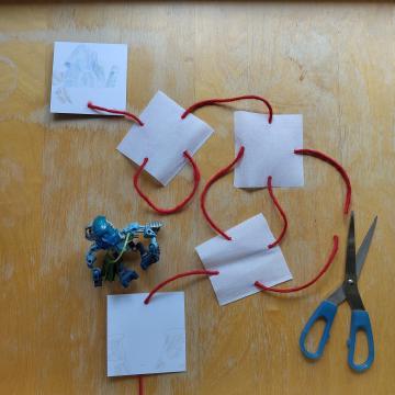 A pair of scissors showing how the string was cut between 2 white squares.