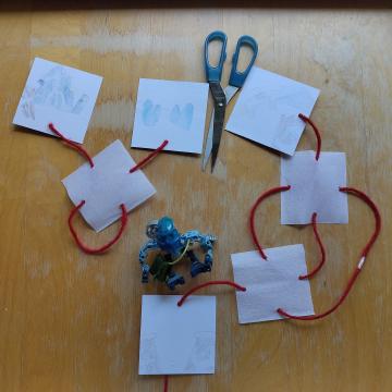 A pair of scissors showing the string being cut in such a way that the squares can now be separated into 2 piles.