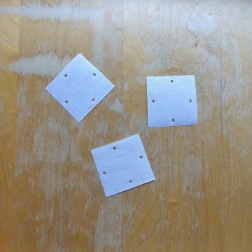 Picture of 3 paper squares with 4 holes each strewn loosely about.